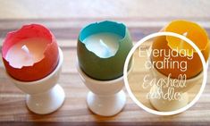 three eggshells with candles in them sitting on a wooden table next to each other