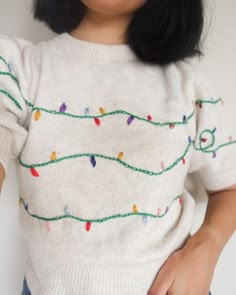 a woman wearing a white sweater with christmas lights on it's chest and arms