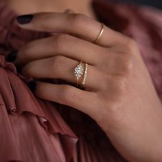 a woman's hand wearing a gold ring with a white flower on the middle