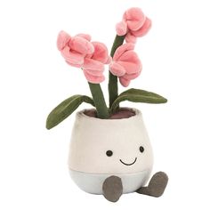 a white vase with pink flowers in it and a smiling face drawn on the side