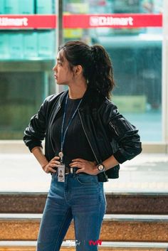 a woman standing in front of a window with her hands on her hips and looking off to the side