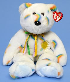 a white teddy bear with rainbow paint on it's face