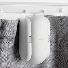 an electric toothbrush holder hangs on the curtain rod in front of a gray and white towel