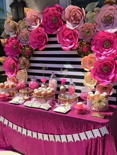 a table topped with lots of desserts and flowers on top of a purple table cloth