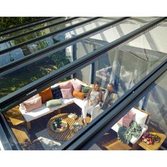 two people sitting on a couch in a room with glass walls and floor to ceiling windows