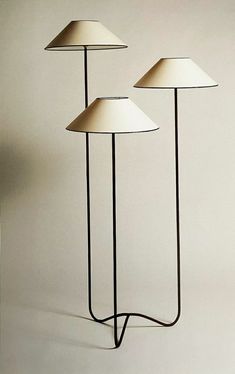 three lamps sitting on top of a white floor next to each other in front of a wall