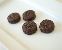 four chocolate cookies sitting on top of a white cutting board