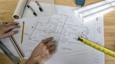 a person is working on some blueprints at a table with pencils and rulers