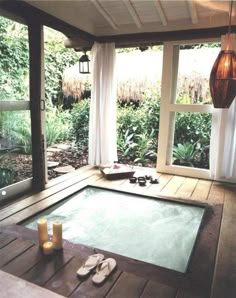 an indoor hot tub with sliding windows that open outside and candles on the floor next to it