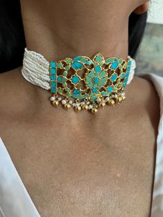 Handcrafted by fine jewelry artisans, this stunning choker necklace set is the perfect accessory for destination weddings and special occasions. Made of 925 silver, the choker features striking turquoise stones and delicate freshwater pearls, adorned with elegant golden ball hangings that add a touch of luxury. This timeless piece is designed to make you stand out. Necklace Weight: 56 grams Materials: 925 Silver, Turquoise, Freshwater Pearls, Golden Ball Hangings Closure Type: Hook closure and is adjustable. The set includes beautifully matching earrings that complete the look. Earrings Weight: 12 grams per pair. Earrings Dimensions: Length is 2 cm and width is 2 cm. Closure Type: Push Back Closure Add this one-of-a-kind, radiant choker set to your collection and let its unique design make Turquoise Beaded Fusion Jewelry, Elegant Handmade Turquoise Choker, Handmade Elegant Turquoise Choker, Turquoise Beaded Jewelry For Celebration, Traditional Turquoise Choker Necklace, Elegant Turquoise Jewelry For Celebration, Festive Turquoise Beaded Jewelry, Elegant Turquoise Choker Necklace, Traditional Turquoise Choker Jewelry