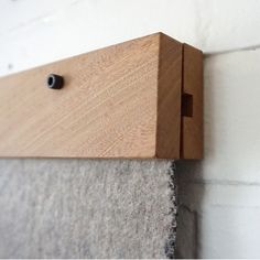 a close up of a wood frame on a wall with a gray fabric under it