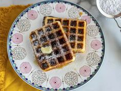 two waffles on a plate with powdered sugar