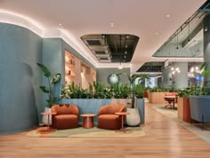 an office lobby with plants on the wall and chairs in the center, along with potted plants