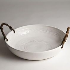 a white bowl with rope handles on the rim