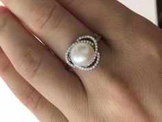 a woman's hand holding a pearl and diamond ring