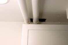 two white pipes are attached to the ceiling above a door in a room with no walls