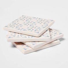 three white ceramic coasters with blue designs on them