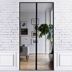 an open door leading to a living room with white brick walls