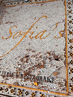 a mosaic tile floor with the word sofita written in gold and black letters