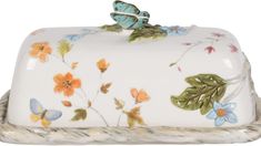 a decorative porcelain box with flowers and butterflies on it's lid, sitting on a rope