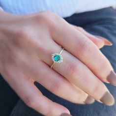 a close up of a person's hand wearing a gold ring with an emerald center