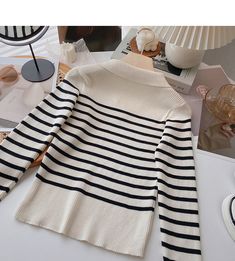 a white and black striped sweater sitting on top of a table next to other items