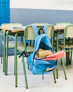 a backpack sitting on top of a chair next to a pile of books and folders