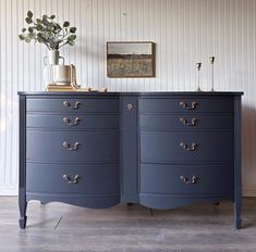 a blue dresser with gold handles and knobs on it's sides, against a white striped wall