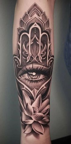 a black and white tattoo with an all seeing eye in the center, surrounded by lotuses