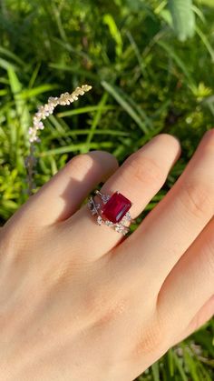 a woman's hand with a ring on it and a red stone in the middle