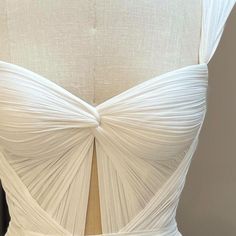 the back of a white wedding dress with pleated details on the waist and shoulders