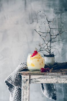 a table topped with a bowl of food and a vase filled with berries on top of it