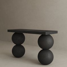 a black table with three balls on it and a white wall in the back ground