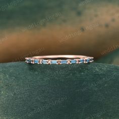 an image of a wedding band with blue stones on the top and bottom half of it