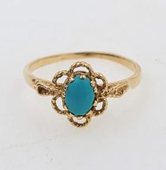 a gold ring with a turquoise stone in the center and filigrees around it