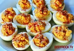 deviled eggs on a white plate with red chili sprinkled on the top