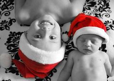 the baby is wearing a santa hat and laying next to his mother in black and white