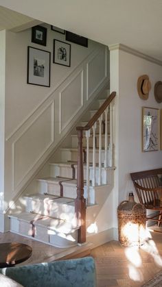 a living room filled with furniture and pictures on the wall next to a stair case