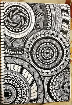 a spiral notebook with black and white doodles on the cover, sitting on top of a