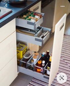 an open drawer in the middle of a kitchen with food and drinks on it's side