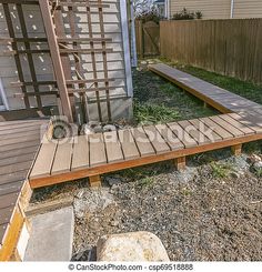 a wooden deck in front of a house next to a fence and yard with grass