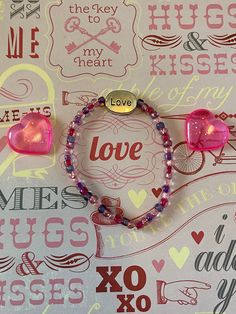 This is a Valentine Love bracelet. It would make a cute gift for a little girl for Valentines Day. It would make a cute addition to a little girl's Valentine outfit.  It has a silver love bead in the middle. It has dark purple, pink, hot pink, and light pink seed beads. It was made with .8mm sturdy stretch string. I tie it several times to prevent breakage. It fits girls ages 6-10. It stretches to fit on the wrist. All items are ready to be shipped I do combined shipping. Items ship in 2-5 busin Girls Valentines Outfit, Bracelets For Kids, Gifts For Valentines, Bracelets For Girls, Valentine Gifts For Kids, Seed Bead Bracelet, Bracelet Love, Love Bracelet, Valentines Outfits