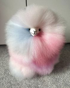 a fuzzy toy with a white and pink fur ball on it's back end