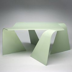 a green table sitting on top of a white floor next to a gray wall in front of it