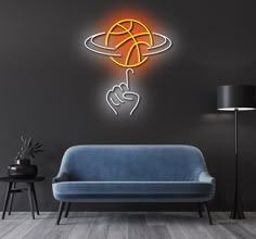 a living room with a blue couch and a neon sign on the wall that says basketball