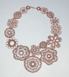 the necklace is made from copper wire and has many circular designs on it's sides