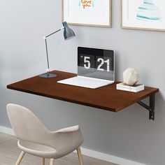 a laptop computer sitting on top of a wooden desk next to a lamp and chair