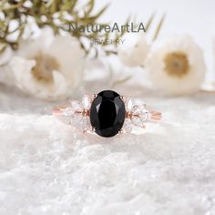 a black and white diamond ring sitting on top of snow covered ground with flowers in the background