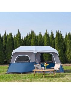 a tent set up in the middle of a field with two chairs and a table