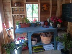 a room filled with potted plants next to a chalkboard